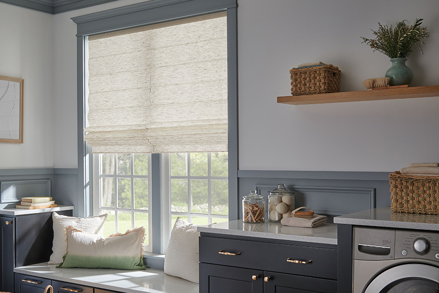 A window shade in a coordinating color makes your laundry room look stylish. White window shade on a window in a blue laundry room