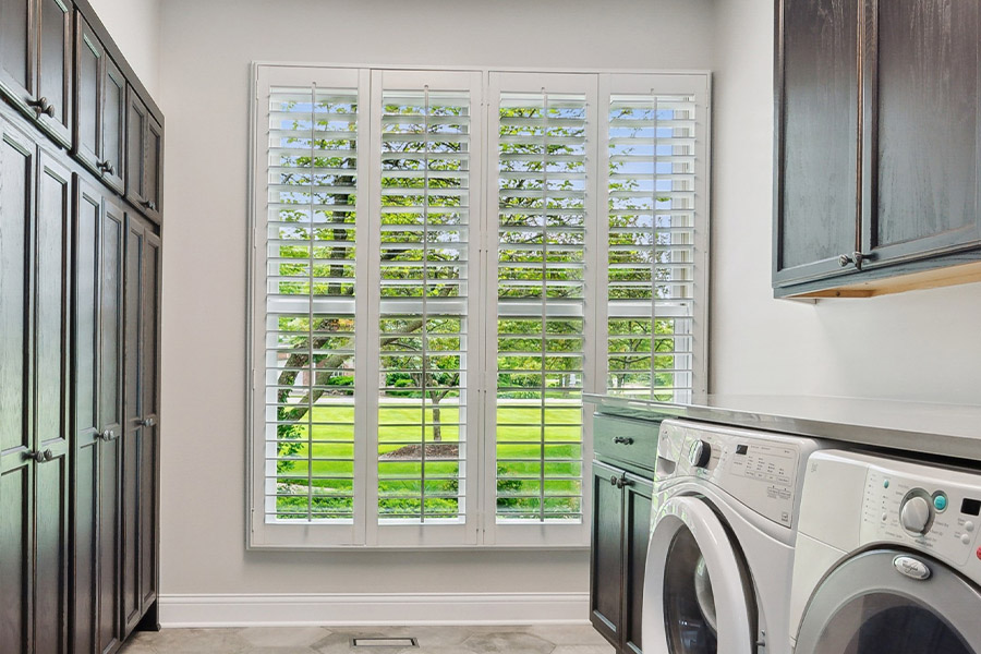 Find the perfect level of natural light for your Hartford laundry room with interior shutters. White Polywood shutters letting light through a laundry room window